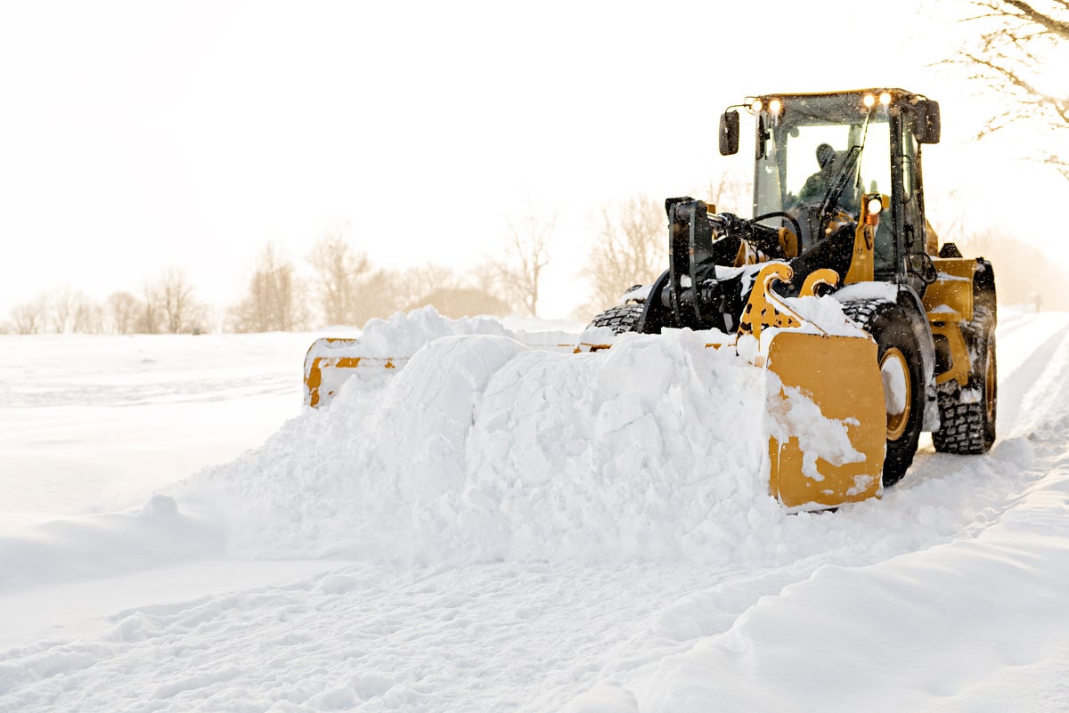 A big yellow snow plow cleaning a road